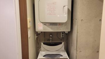 Ein kleines Badezimmer mit Toilette, Waschmaschine und Warmwasserbereiter.