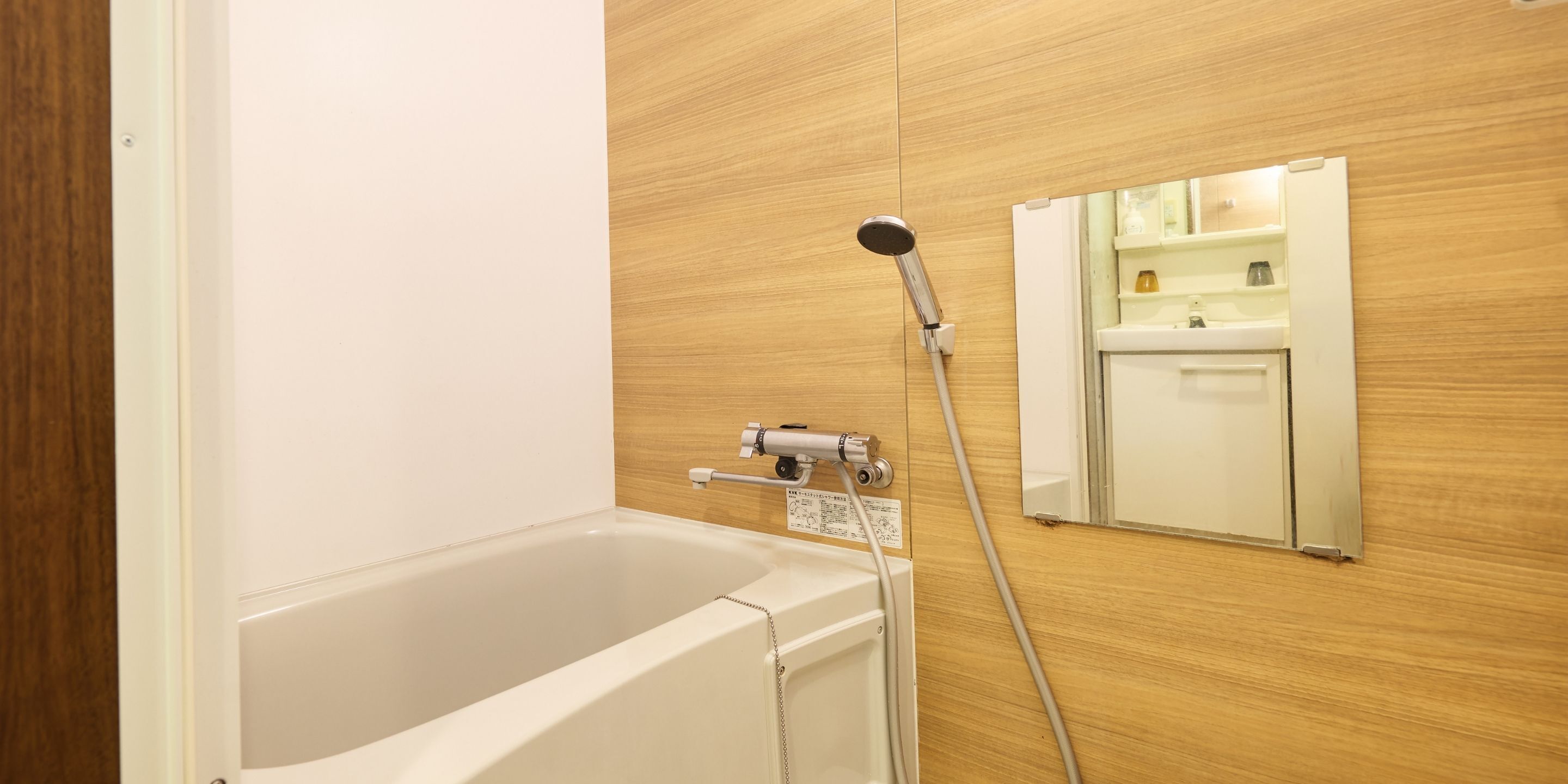 A bathroom with a bathtub, a showerhead, and a mirror.