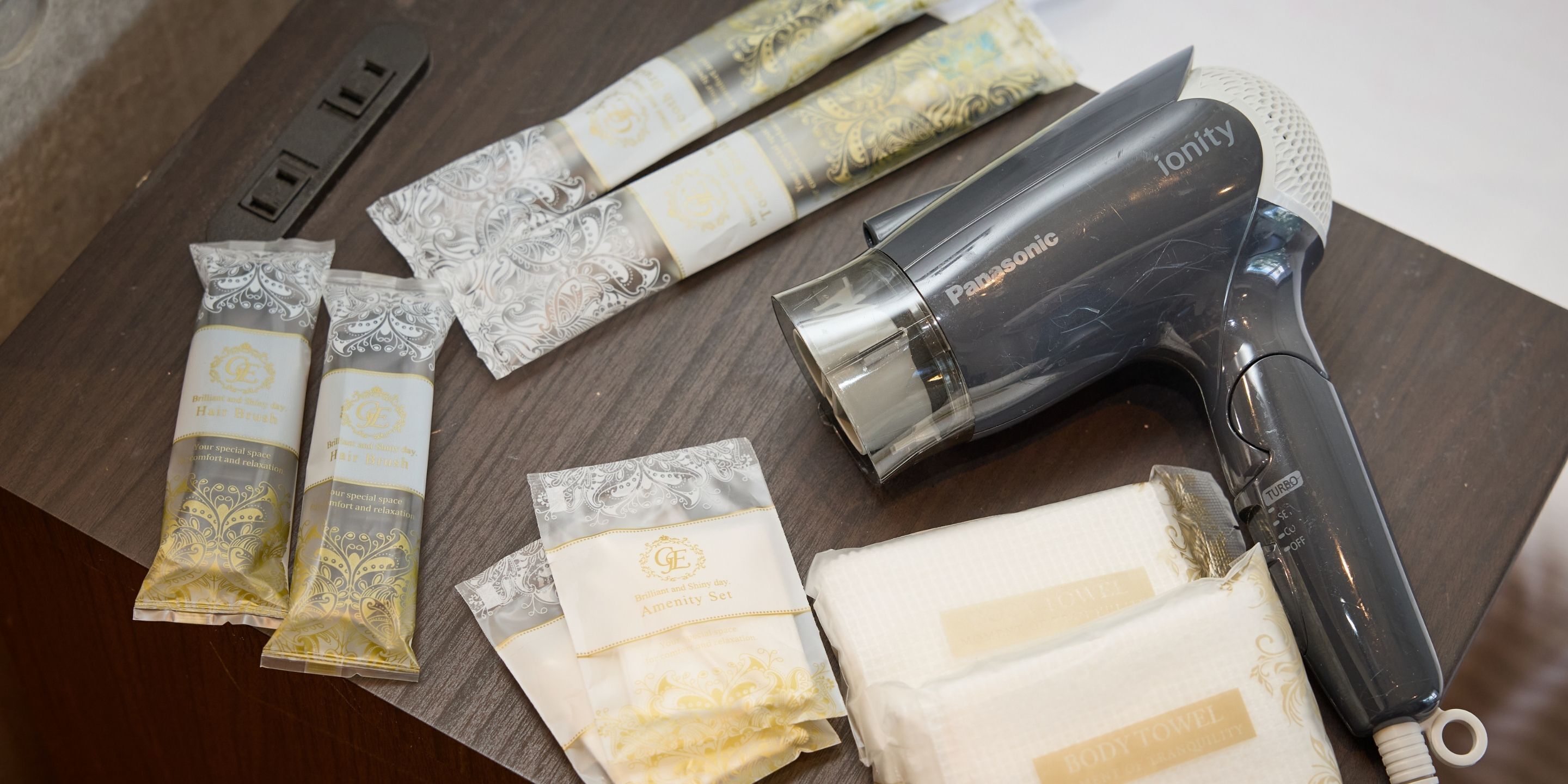 A Panasonic hair dryer, several hairbrushes, and hair care products on a wooden surface.