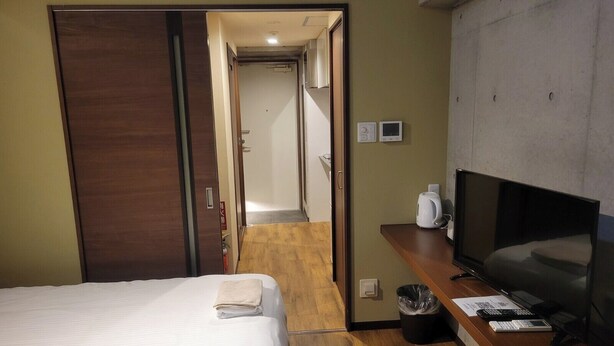 A hotel room with a bed, a TV, a desk with a computer, and a trash bin. - New Normal Hotel in NAHA WAKASA (Naha)