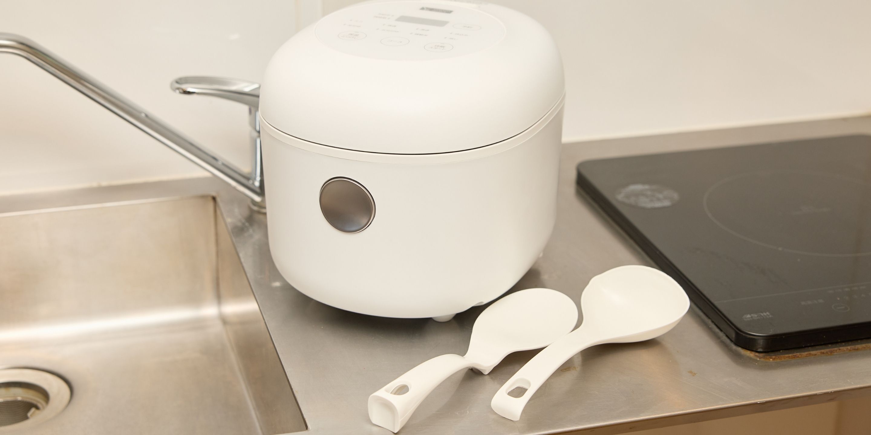 A white kitchen appliance, possibly a rice cooker, with a digital display and a control panel.