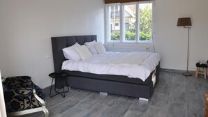 A bedroom with a bed, a chair, a lamp, and a window.