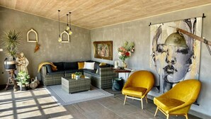 A living room with a sofa, two yellow chairs, a coffee table, and a painting on the wall.