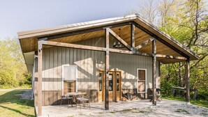 A single-story building with a covered porch, a patio with outdoor seating, and a small garden area.
