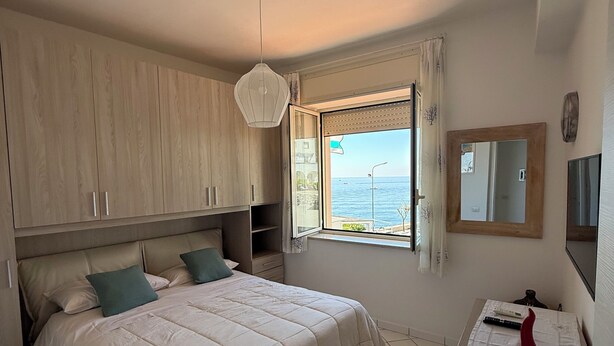 Camera da letto con un letto, un comodino, uno specchio e una finestra vista mare.