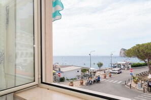 A coastal view from a window overlooking a street with parked scooters, a no entry sign, and a building with a sign that reads 'Coco'. - Masticiello House (Nerano)