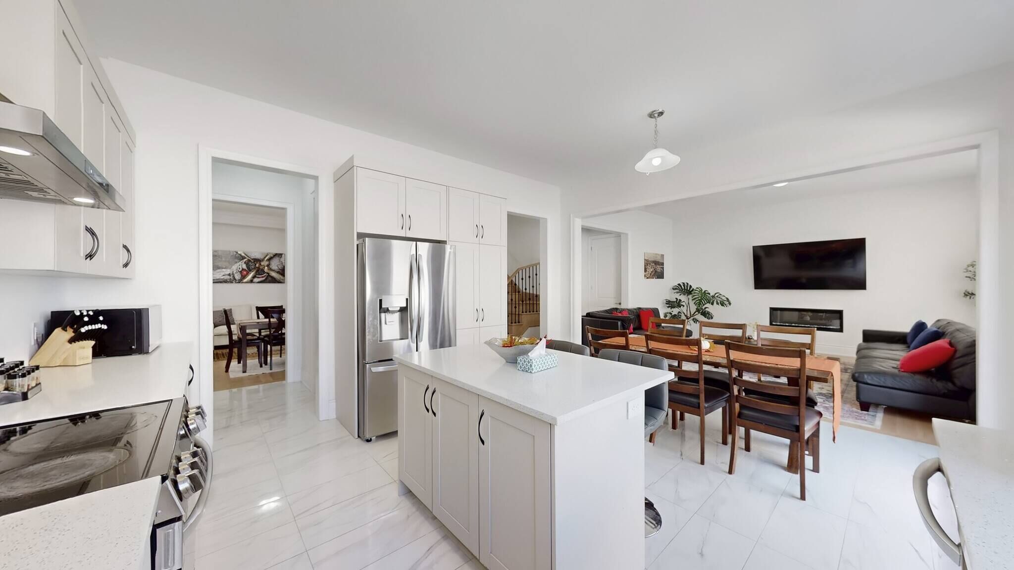 A modern kitchen with a central island, stainless steel appliances, and a dining area with wooden chairs and a table.