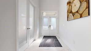 A hallway with white doors, a black and white rug, and a wooden log wall art piece. - Private 5-bedroom Caledon Home Comfort, Style, and Nature! (Caledon)