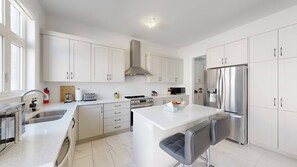 A modern kitchen with white cabinetry, stainless steel appliances, and a central island with seating. - Private 5-bedroom Caledon Home Comfort, Style, and Nature! (Caledon)