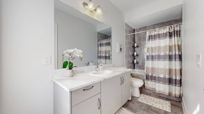 A bathroom with a white sink, mirror, and shower curtain. - Private 5-bedroom Caledon Home Comfort, Style, and Nature! (Caledon)