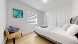 A bedroom with a bed, a chair, a window with blinds, and a door. - Private 5-bedroom Caledon Home Comfort, Style, and Nature! (Caledon)