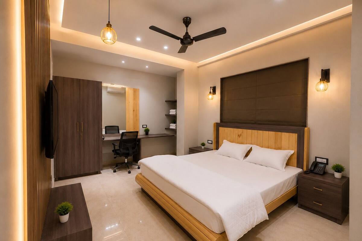 A modern bedroom with a large bed, a desk, a chair, a wardrobe, and a ceiling fan.