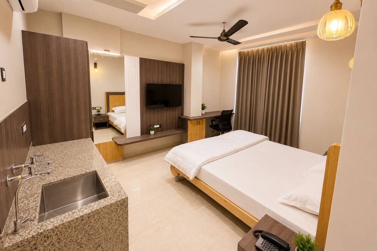 A modern hotel room with a bed, desk, and built-in TV.