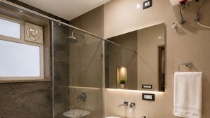 A modern bathroom with a glass-enclosed shower, a marble sink, and a toilet. - Studio 24 (Jaipur)