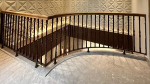 A modern interior with a curved staircase, geometric wall patterns, and recessed lighting. - Studio 24 (Jaipur)