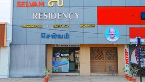 Un immeuble portant une enseigne indiquant  « Résidence Selvam » et offrant les commodités suivantes : piscine, salle de réception et terrain de badminton.
