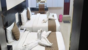 Une chambre d’hôtel avec deux lits, chacun recouvert d’une couverture blanche à motifs, et des serviettes disposées sur les lits.