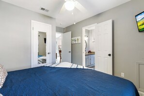 A bedroom with a large bed, a ceiling fan, and a view into the adjacent bathroom. - Beachfront South Padre Island condo with bay views, sunsets, and SpaceX launches from your private deck. Sleeps 6 in 2 bedrooms (king and queen) plus convertible sofa. Chef's kitchen, WiFi, washer/dryer, fire pit, grill, free parking. Pet-friendly. (South Padre Island)