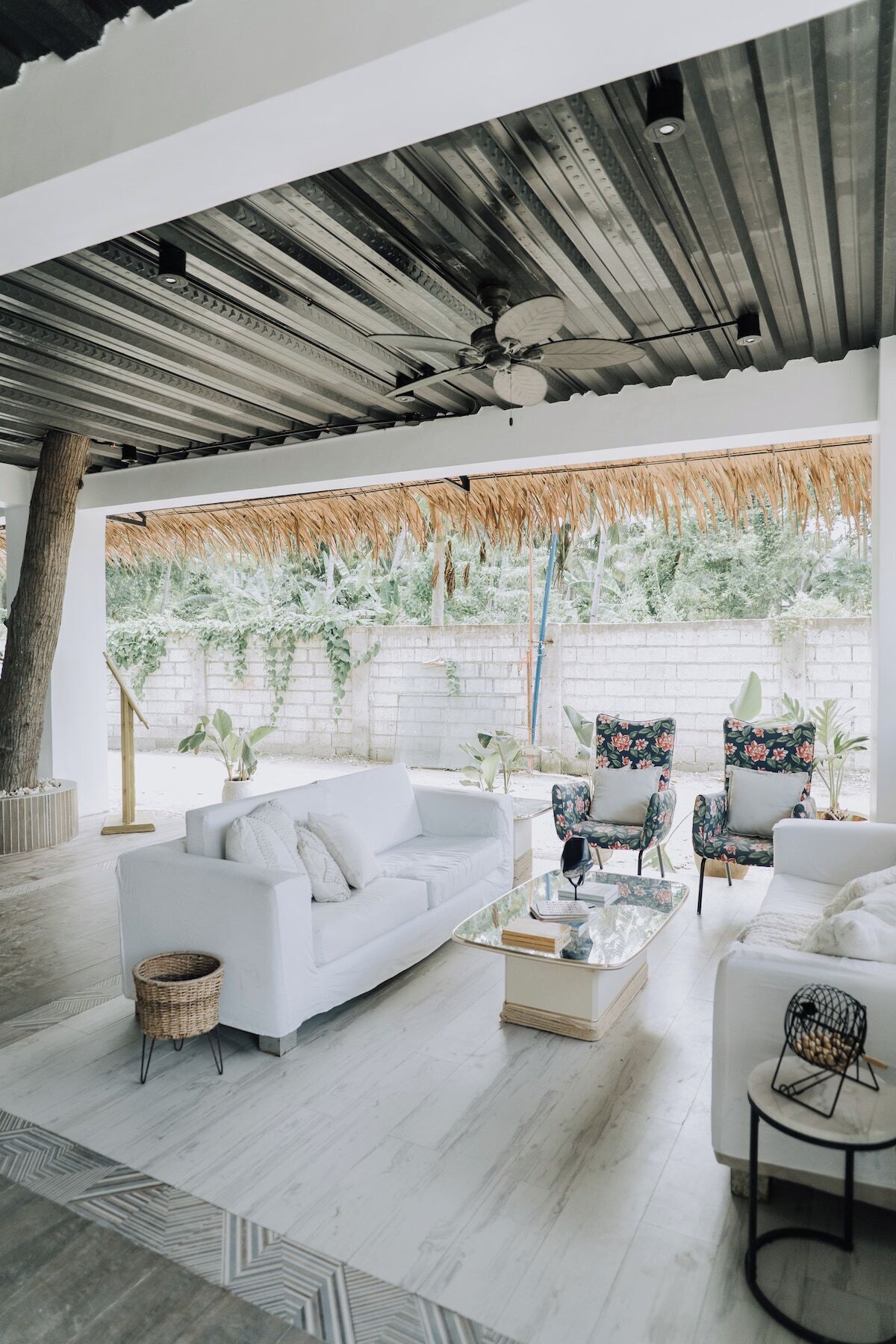A modern living room with a white sofa, two armchairs, a coffee table, and a large window with a view of greenery.