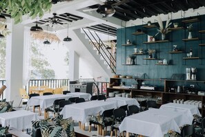 A restaurant with multiple tables, chairs, and a staircase.