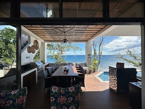 An outdoor dining area with a view of the sea, a grill, and a pool.