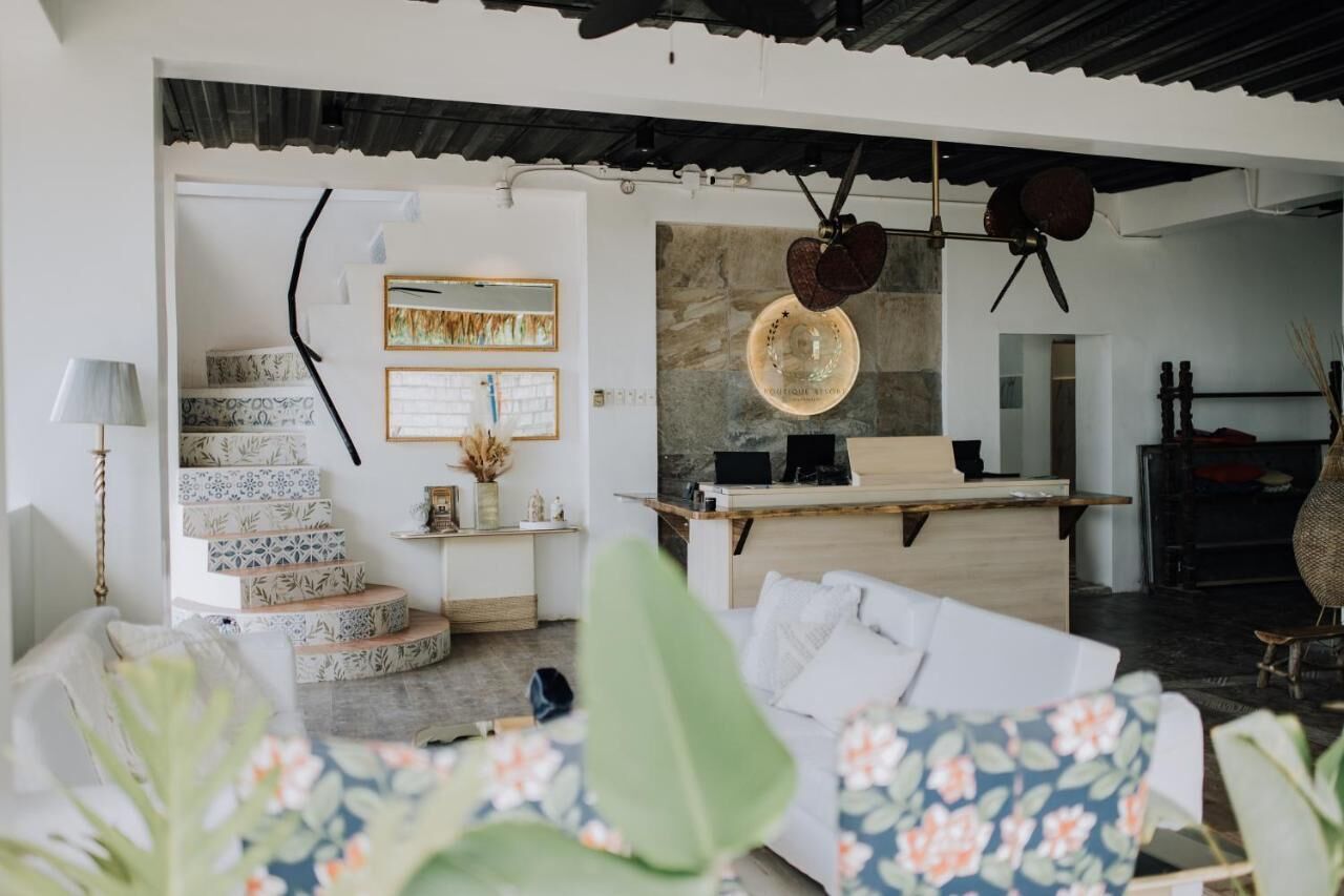 A modern interior with a staircase, a sofa, a desk, and a hanging light fixture.