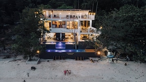 A two-story building with a pool, surrounded by trees.