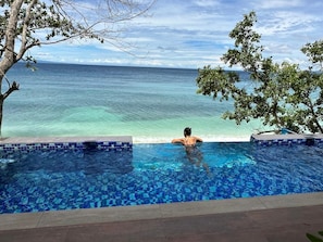 A person in a swimming pool with a view of the ocean.