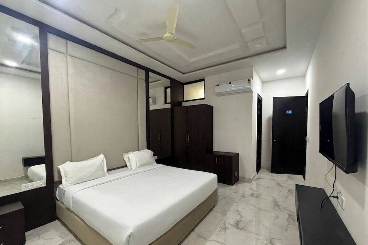 Un dormitorio con cama, ventilador de techo, televisor y armario.