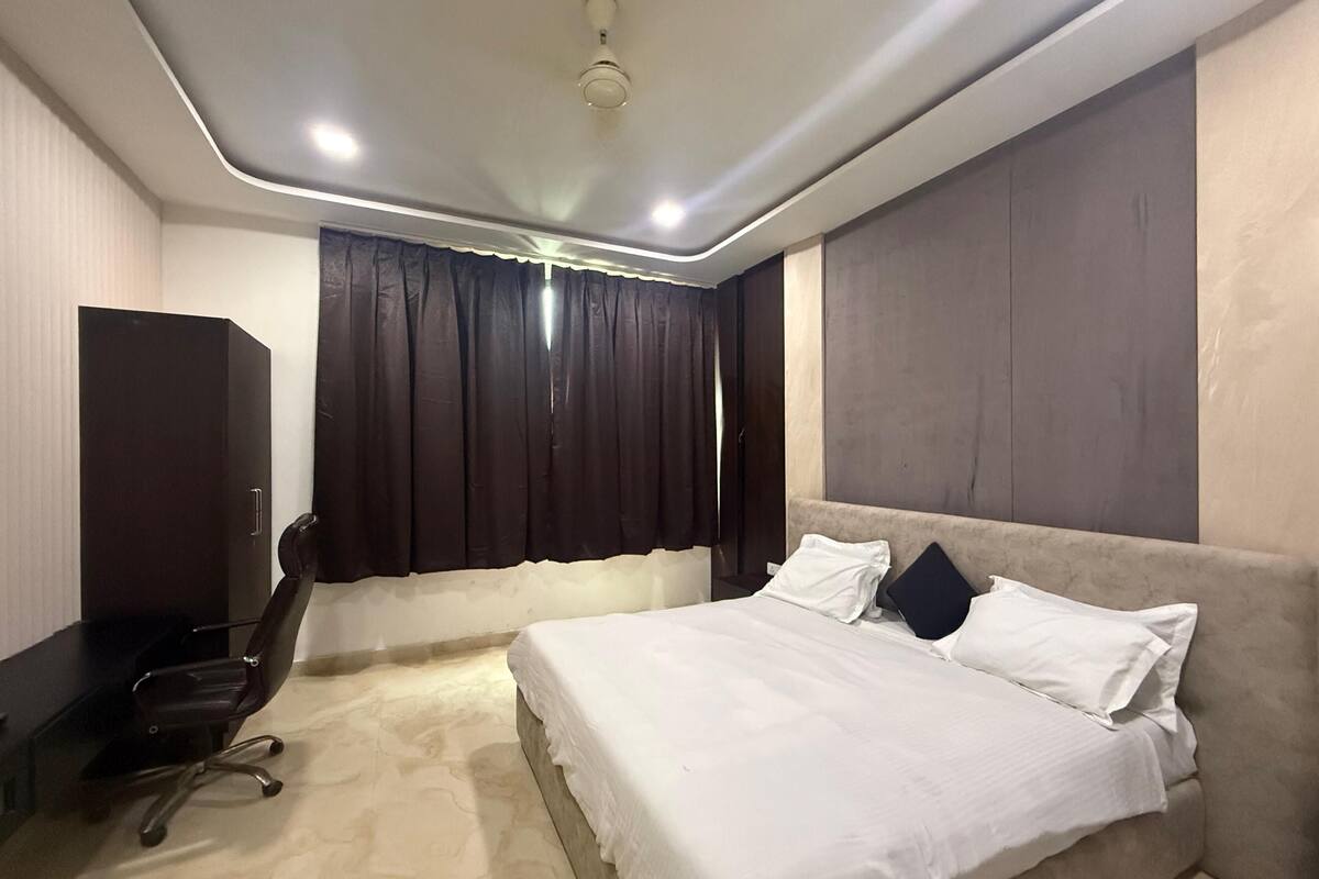 Una habitación de hotel moderna con cama, escritorio, silla y armario.
