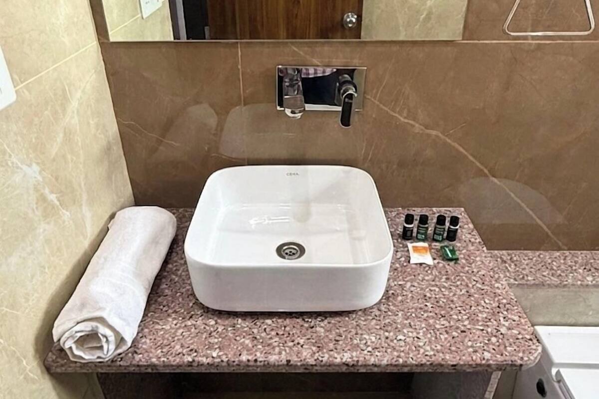 Un baño con lavamanos blanco, una toalla y dispensador de jabón.