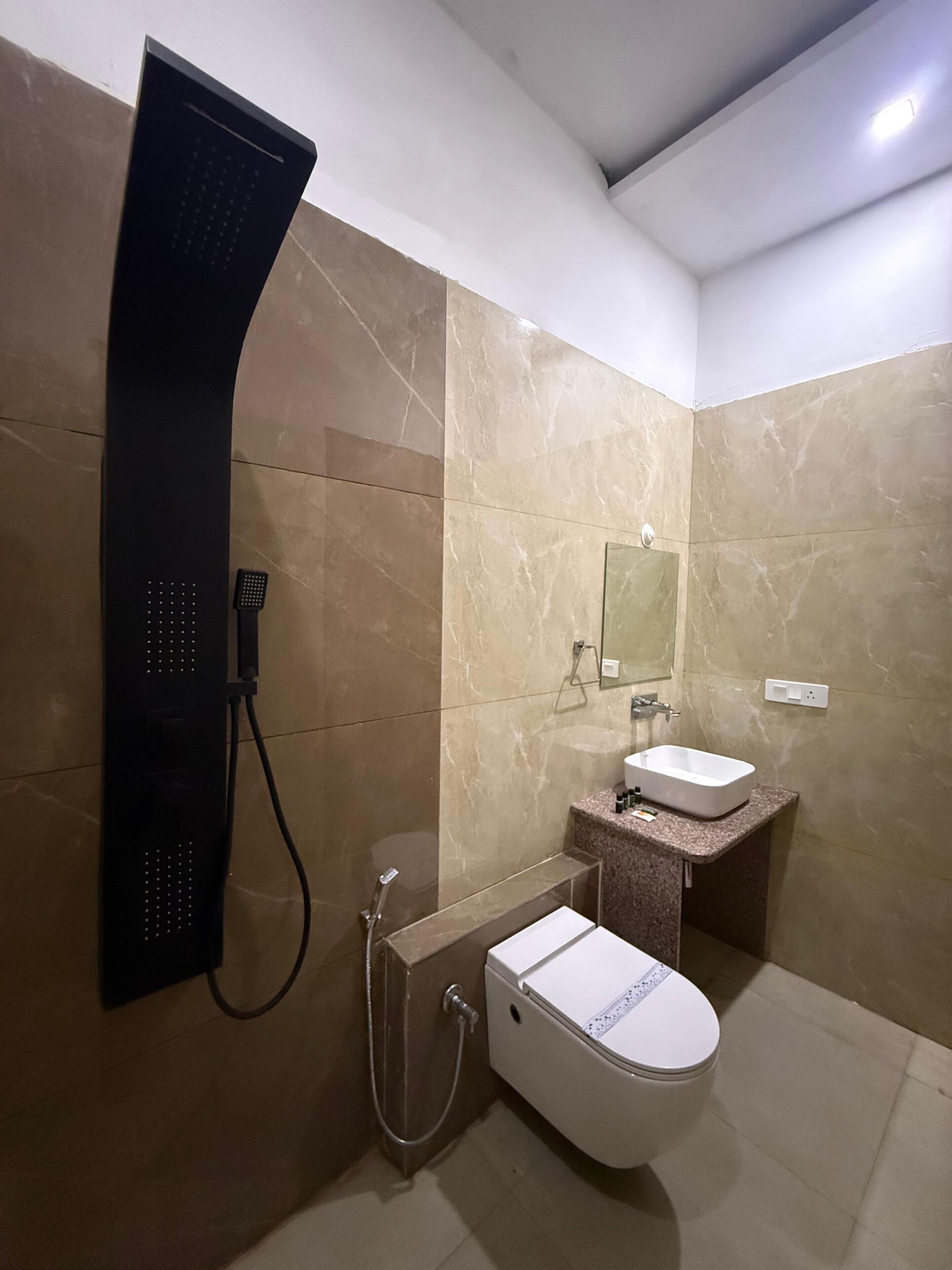 Une salle de bain moderne équipée d’une douche, de toilettes, d’un lavabo et d’un miroir.