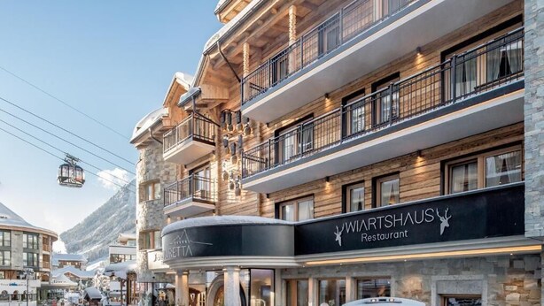 Un edificio de varios pisos con un restaurante llamado 'WARTSHAUS Restaurant' en la planta baja.