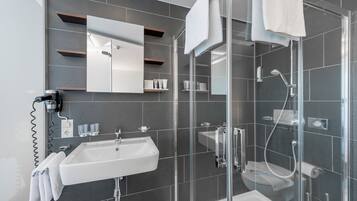 A modern bathroom with a glass-enclosed shower, a white sink, and a mirror above the sink.