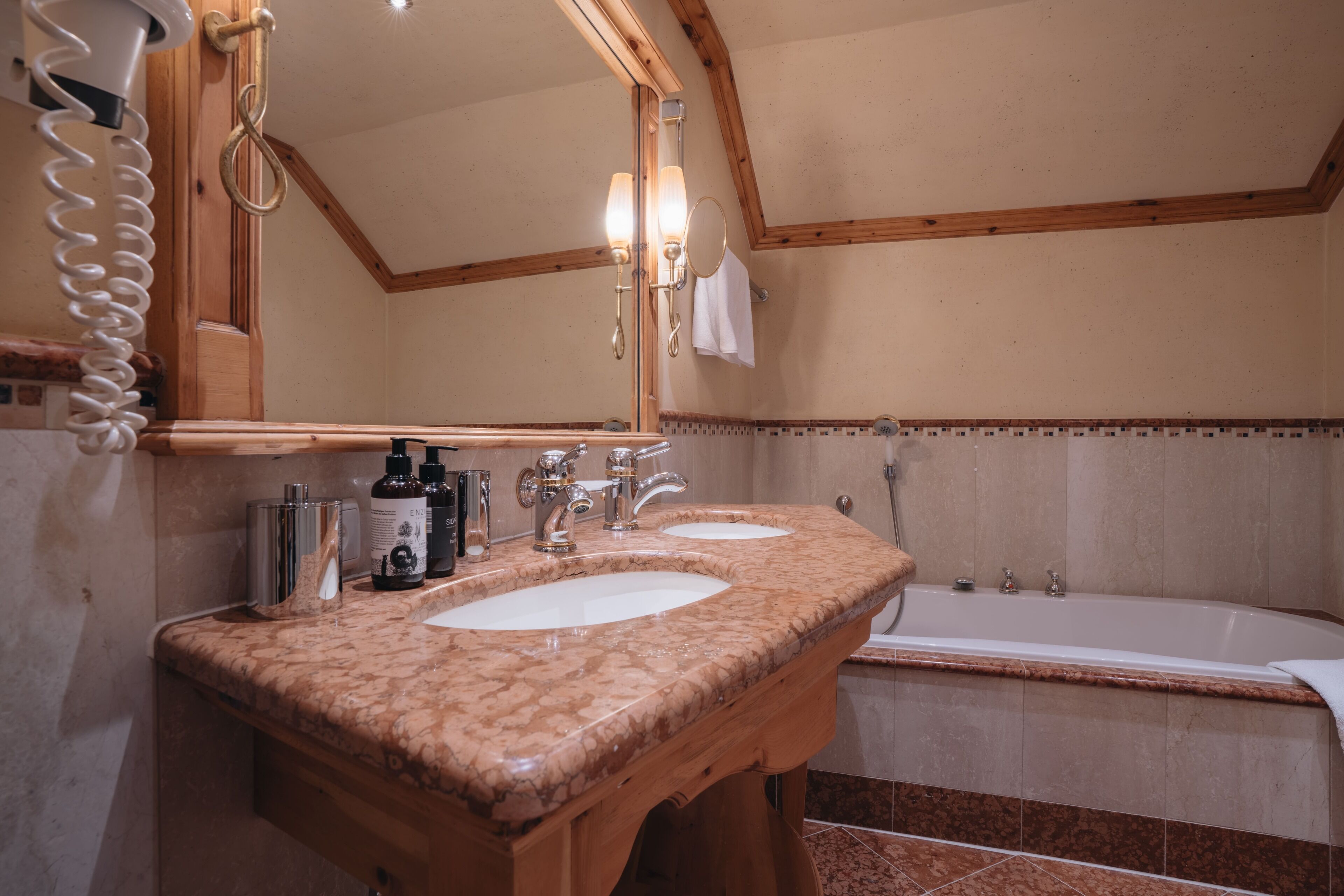Un baño con dos lavamanos, una bañera, un espejo grande y un perchero para toallas.