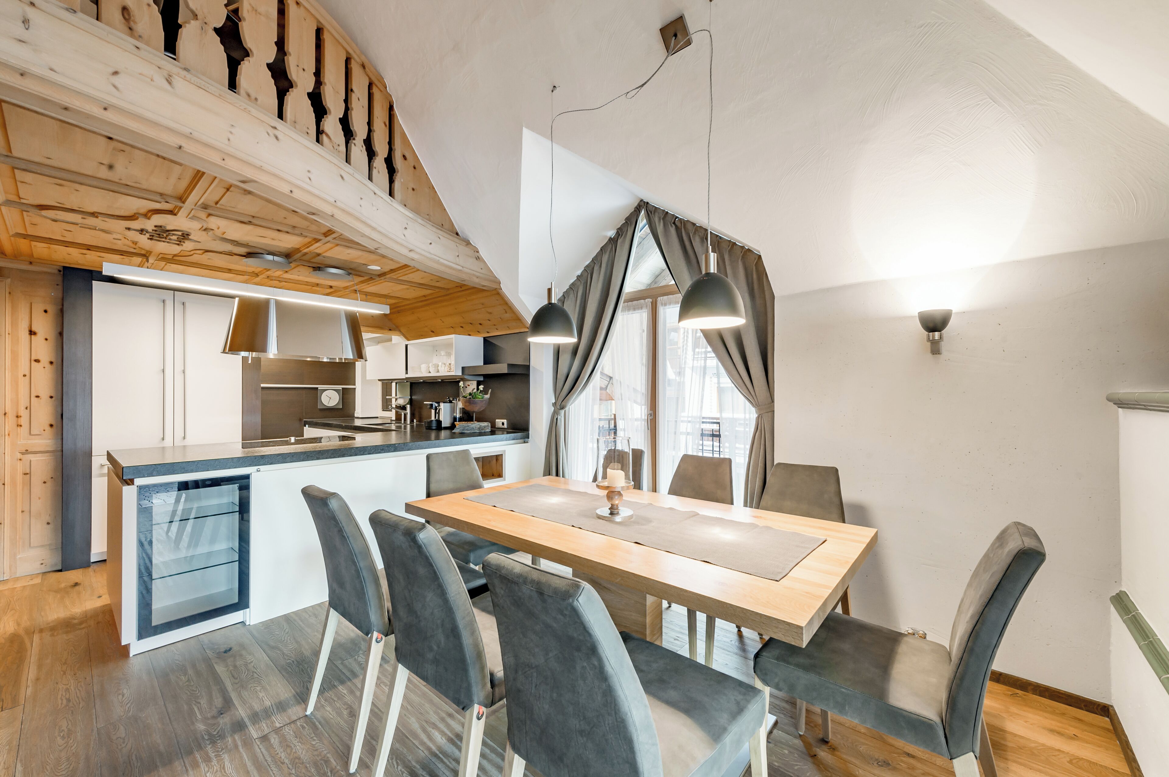 Une cuisine moderne avec un plafond en bois, un coin repas avec une table et des chaises, et un îlot de cuisine.