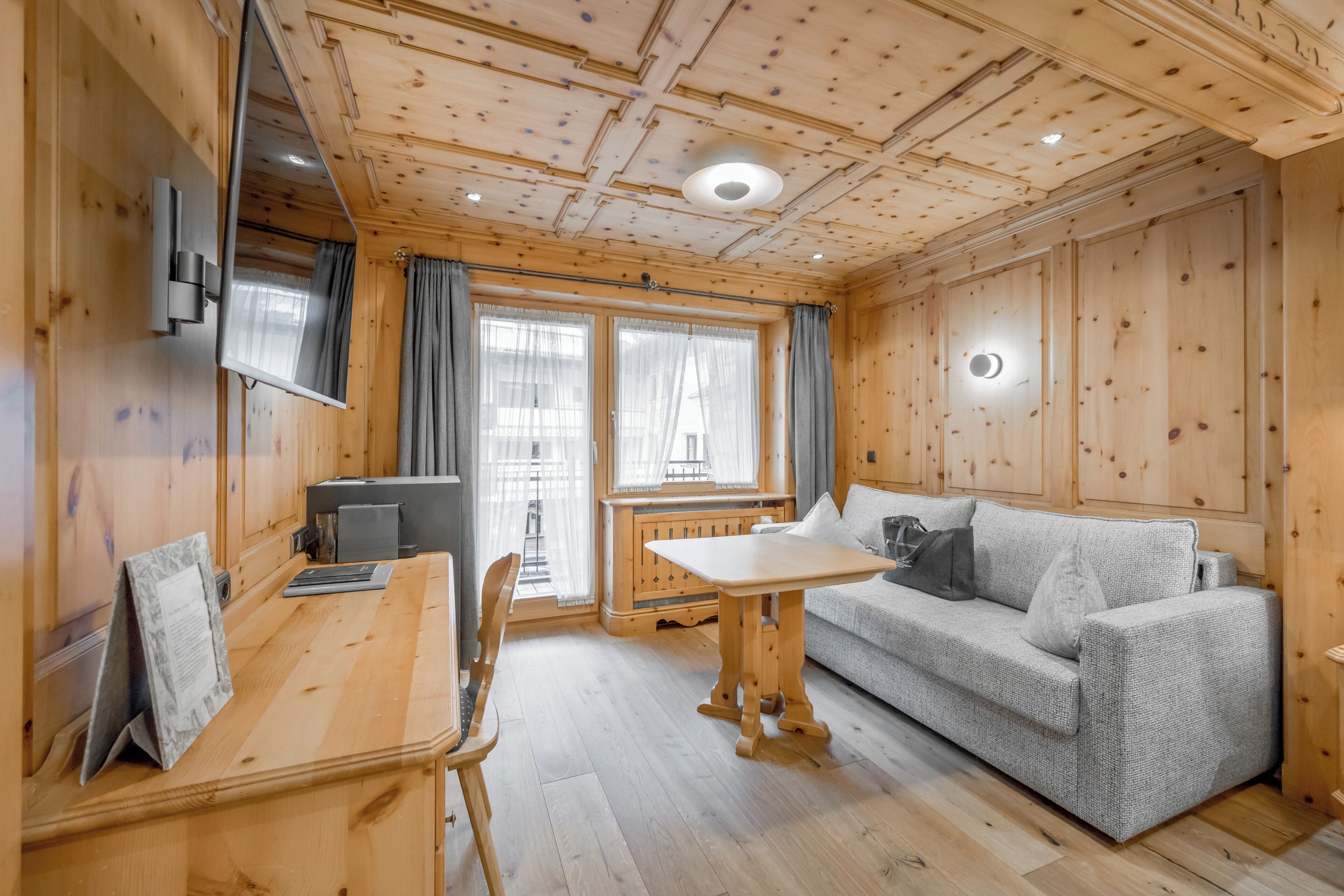 A wooden interior with a sofa, table, and TV.