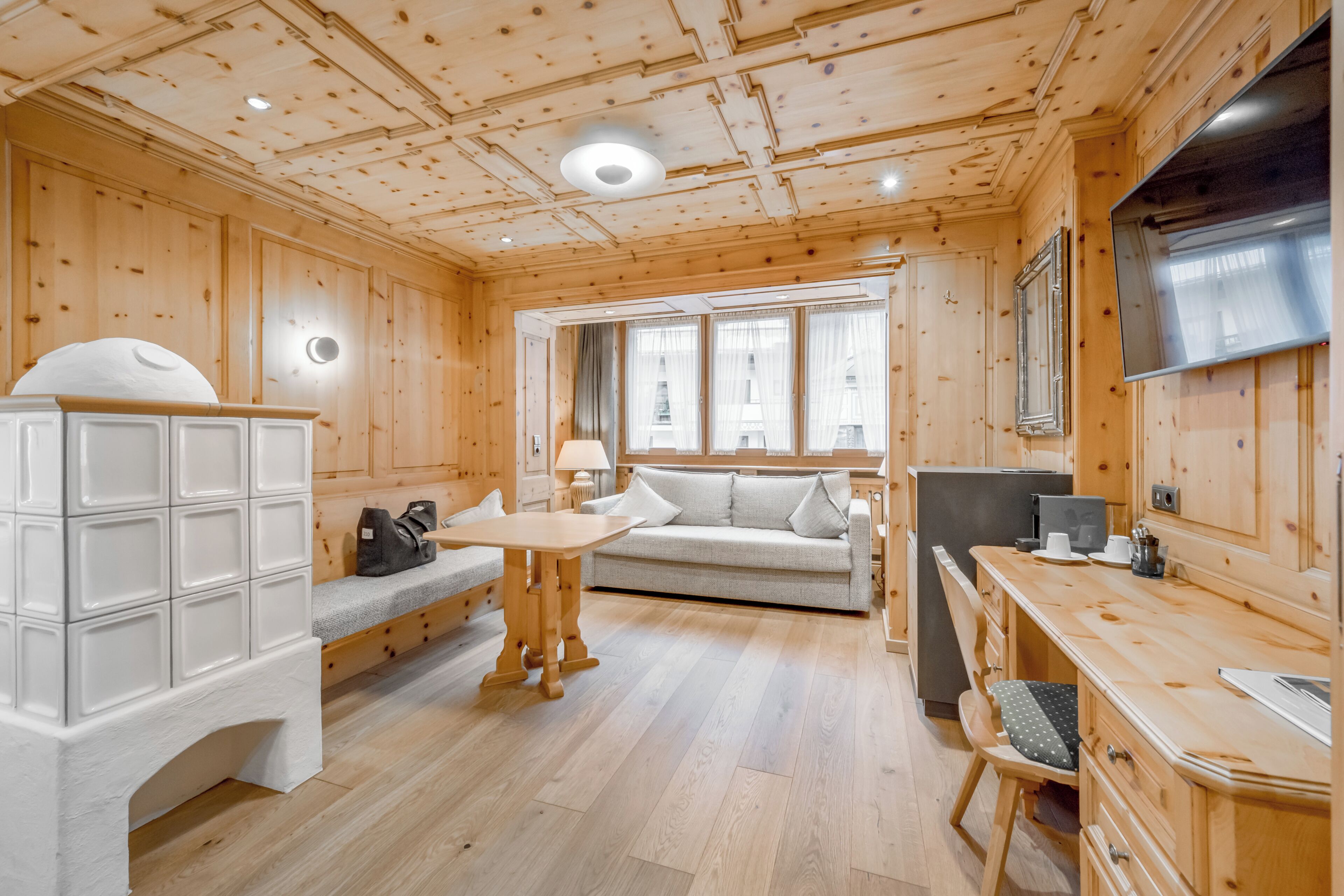 A wooden interior with a sofa, table, and cabinets.