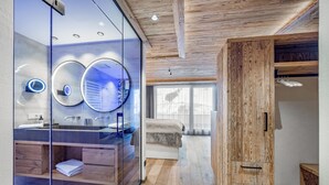 Un baño moderno con mampara de vidrio, techo de madera y un espejo grande.