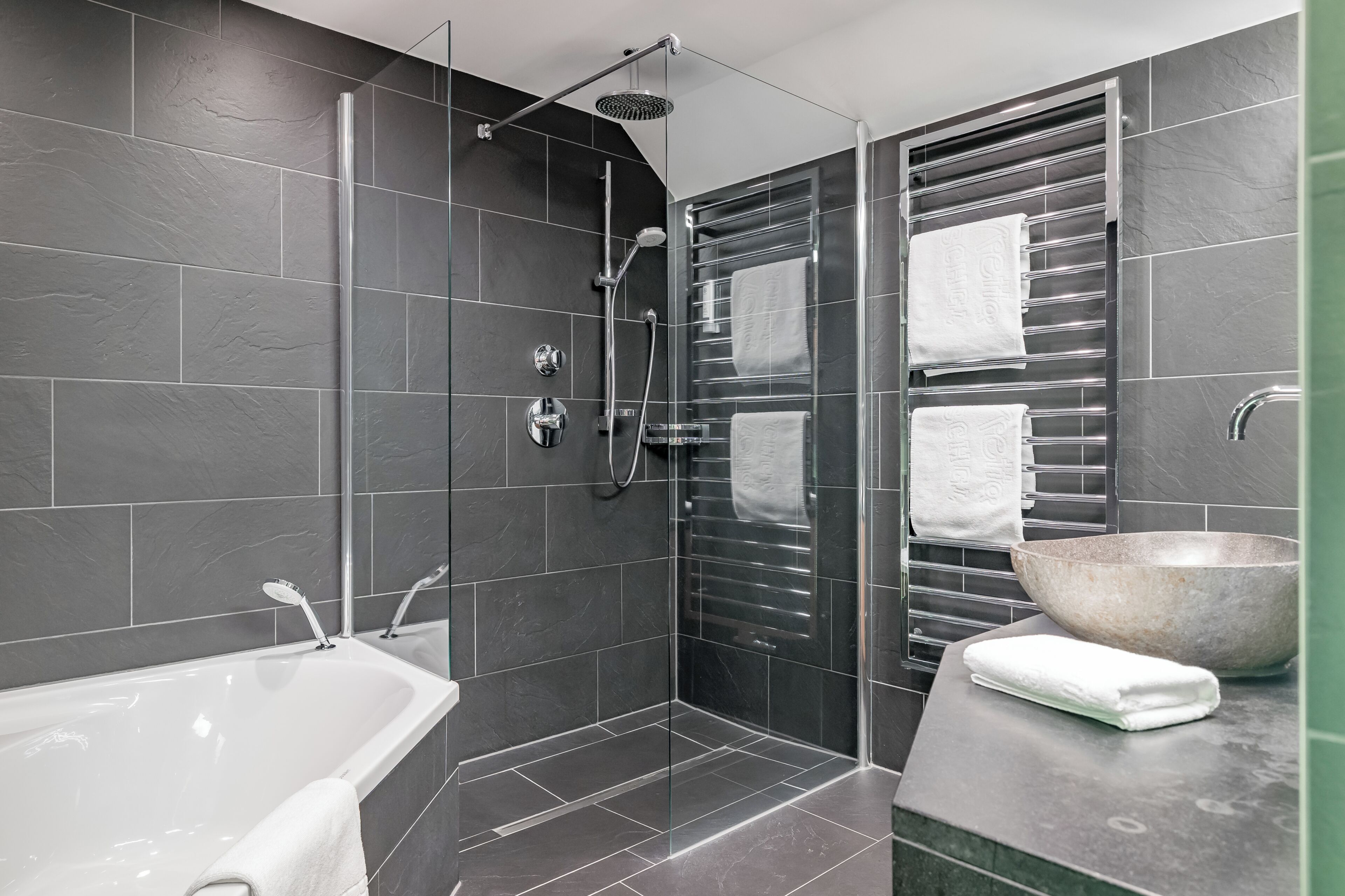 Un baño moderno con ducha envuelta en vidrio, una bañera y un lavamanos grande.
