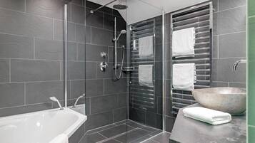 Un baño moderno con ducha envuelta en vidrio, una bañera y un lavamanos grande.