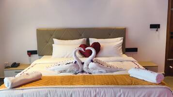 A hotel room with a bed, a bedside table, a nightstand, a wall-mounted air conditioner, and a door.