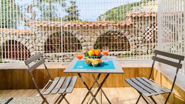 Un patio al aire libre con una mesa lista para dos personas, un muro de piedra y vistas a zonas verdes.