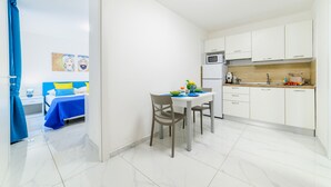 Una habitación de hotel pequeña con cama, una mesa de comedor y kitchenette.