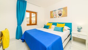 Un dormitorio con cama, cortinas, una obra de arte y una mesita de noche.