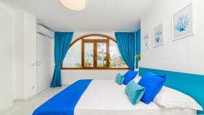 Un dormitorio con cama, cortinas, ventana y cuadros en la pared.