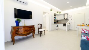 A modern kitchen with white cabinets, a built-in oven, and a dining area with a table and chairs. - Maison Ann in Sorrento (Sorrento)