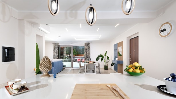 A modern kitchen with a central island, a dining area with a table and chairs, and a living room with a sofa and a TV. - Villa Elios in Massa Lubrense (Massa Lubrense)