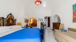 Una habitación con cama, sofá, escritorio y una silla. Hay dos puertas y una ventana.