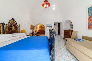 A room with a bed, a sofa, a desk, and a chair. There are two doors and a window. - Casa Bouganville in Positano (Positano)